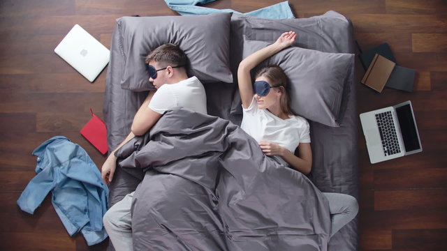 Time lapse of sleeping couple on the bed, man stealing sheet then girlfriend pulling it over on her, he rolling and snuggling up with her