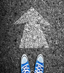 pair of feet standing on road with white arrows