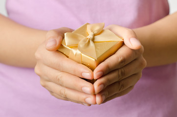 Woman holding golden giftbox by hand