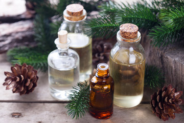 Obraz na płótnie Canvas Bottles with fir tree essential aroma oil on aged wooden backg