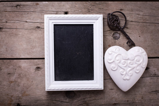 White  decorative  heart, empty blackboard and vintage key on ag