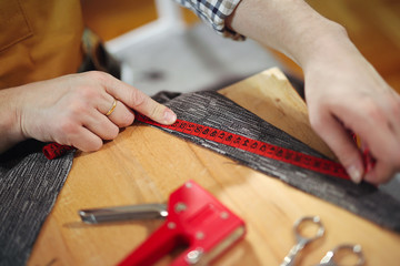 Man upholstering chair in his workshop, measure