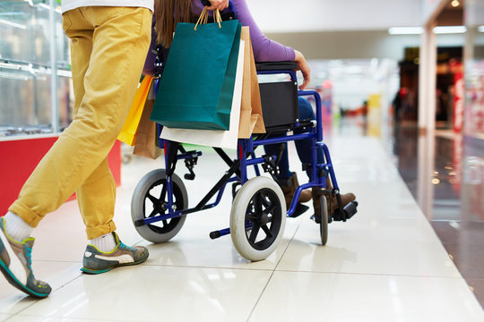 Caring guy helping his girlfriend on wheelchair with shopping