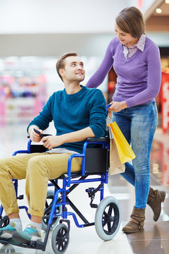 Pretty girl and her boyfriend in wheelchair shopping together