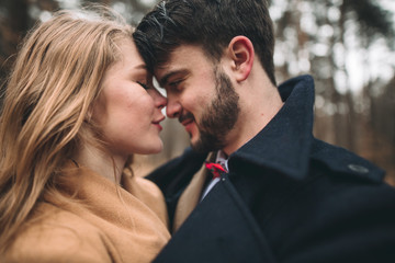 Gorgeous newlywed bride and groom posing in pine forest near retro car in their wedding day