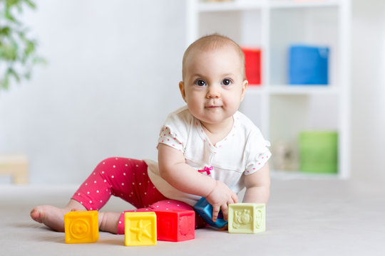 beautiful baby plays cubes on the floor and smiling