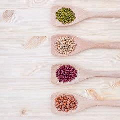 Assortment of beans and lentils in wooden spoon on wooden backgr