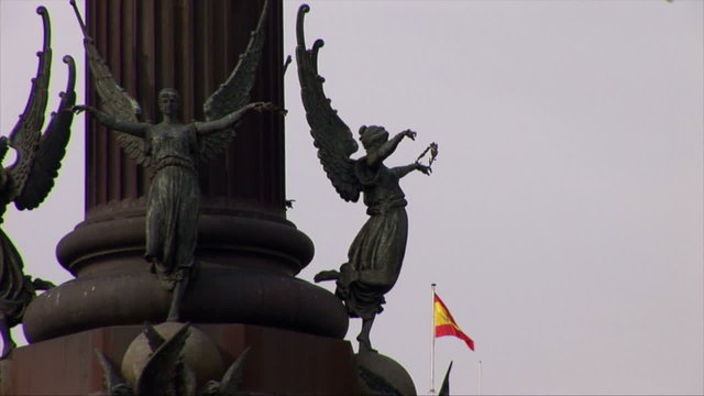 Statues on the Colon Memorial with the Spanish flag in the background