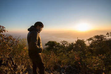 Fototapeta premium Young southeast asian man standing at mountain view in the morni