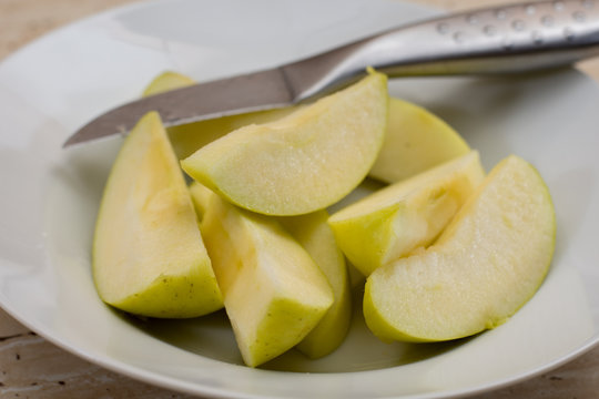 Sliced green sweet apple in the plate and knife