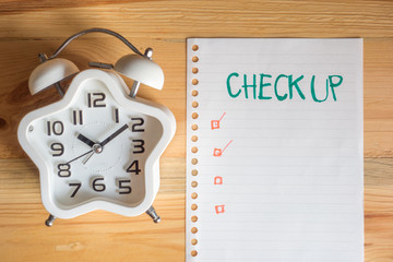 Health check up period concept, top view clock and paper note on wood table