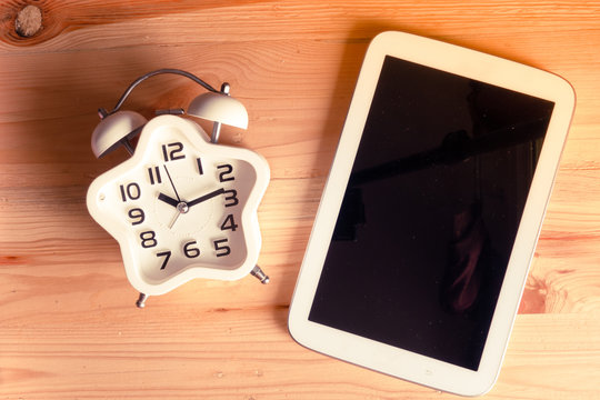 Education concept. Top view Alarm clock on wood table with Tablet PC, vintage tone
