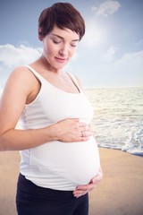 Composite image of relaxed pregnant woman holding belly