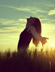 Silhouette of a girl in a barley field at sunset