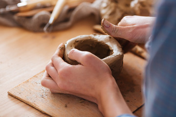 Woman hands making pot using clay in pottery studio