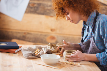 Obraz na płótnie Canvas Redhead attractive young woman creating an earthen jar
