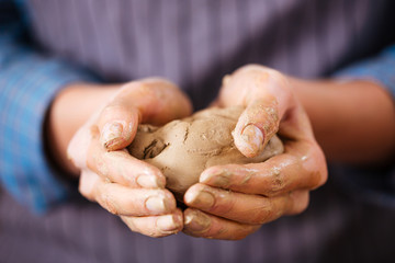 Young woman potter hands holding piece of clay