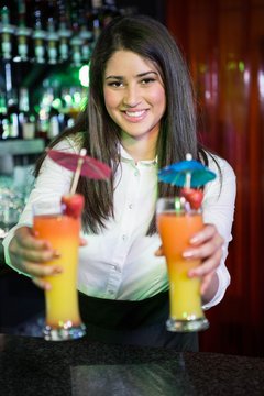 Portrait of pretty bartender serving cocktail at bar counter
