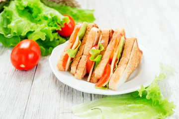 
breakfast or lunch , sandwiches with cheese , sausage , tomato, lettuce and mayonnaise on a wooden background