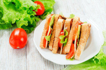 
breakfast or lunch , sandwiches with cheese , sausage , tomato, lettuce and mayonnaise on a wooden background