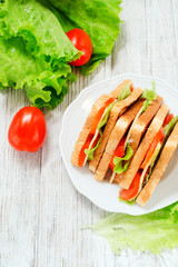 
breakfast or lunch , sandwiches with cheese , sausage , tomato, lettuce and mayonnaise on a wooden background