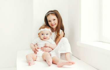 Two sisters children playing together at home in white room