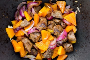 Cooking traditional meat stew with beef, pumpkin, onions, fried