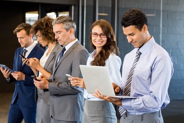 Businesspeople using mobile phone, lap top and digital tablet