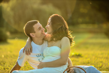 Happy pregnant couple sitting on the grass in park