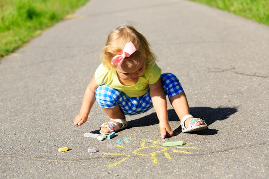 cute little girl drawing sun on a street