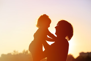 silhouettes of father and little daughter at sunset