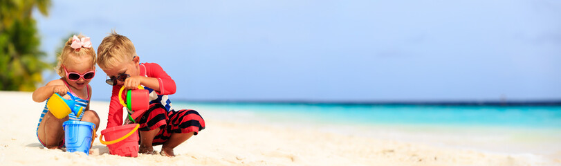 cute little boy and toddler girl play on beach