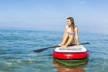 Woman sitting over a paddle surfboard