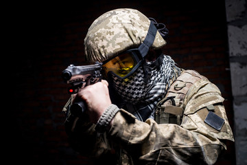 Man in military uniform with gun in his hand/Soldier in uniform with helmet and mask aiming from gun at the camera