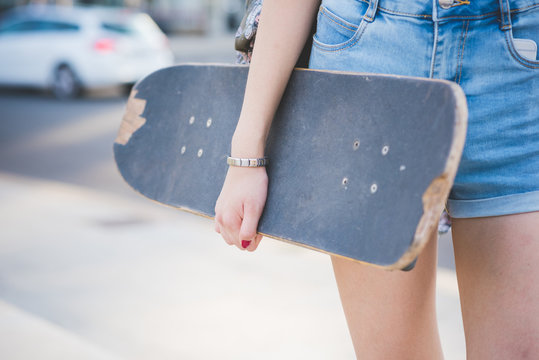 Close up on the hand of young woman holding a skateboard - sport