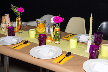 Decorated table in mexican style ready for dinner. Beautifully decorated colorful table set with flowers, candles, plates and serviettes for wedding or another event in the restaurant.