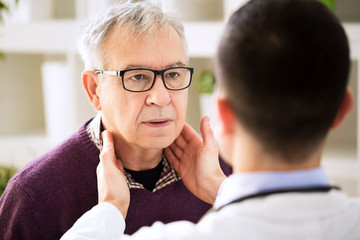 Doctor examining old patient lymph glands