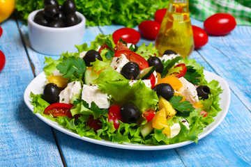 Greek salad with fresh vegetables, feta cheese and black olives on a wooden background