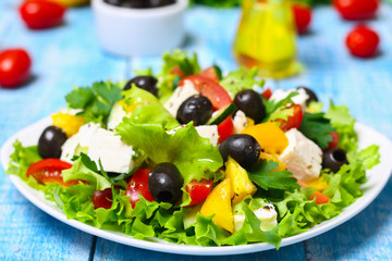 Greek salad with fresh vegetables, feta cheese and black olives on a wooden background