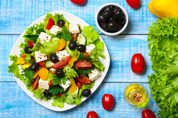 Greek salad with fresh vegetables, feta cheese and black olives on a wooden background