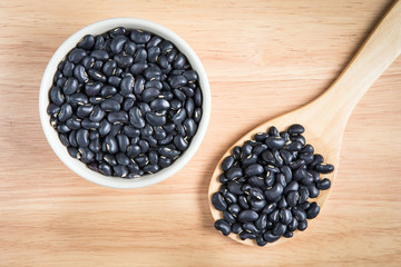 bowl of black bean and a scoop of black bean on the wood backgro