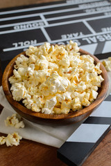 Movie clapper with popcorn on wooden background