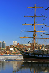 reflection sailing ship and buildings of the city of Vladivostok in winter sea surface