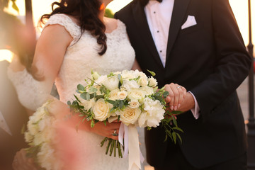 Bride and groom holding hands with bridal bouquet