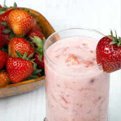 Fresh organic strawberries in bowl on white wooden background