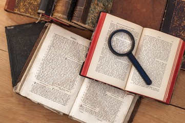 Antiquarian open book and magnifying glass on the table