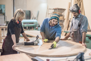 Female carpenter working in workshop / Carpenters work on wood plank in workshop