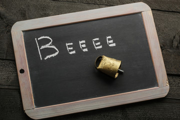 Antica Campanella dorata su lavagna con scritto Beee
