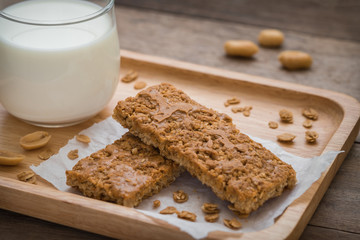 Granola bars on wooden plate and glass of milk