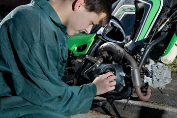 Teenage mechanic working on a motorbike - obrazy, fototapety, plakaty